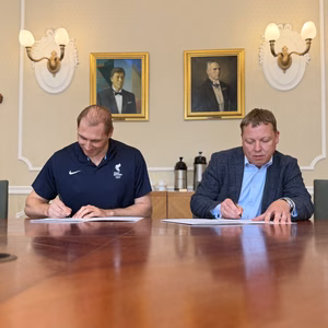 People signing documents at a meeting table